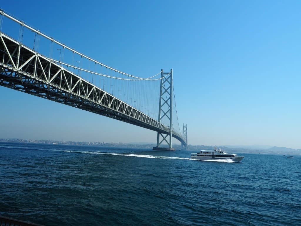 Puente Akashi Kaikyo con un ferry bajo cielo azul